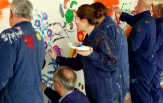 MitarbeiterInnen malen gemeinsam am teampainting Firmenevent