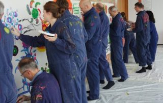 MitarbeiterInnen malen gemeinsam am teampainting Firmenevent