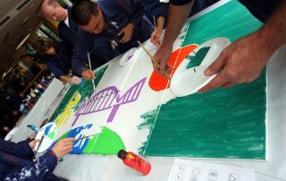 MitarbeiterInnen von Daimler Logistics malen gemeinsam während einer kreativen Teambuilding Aktion ihre neuen Kulturelemente