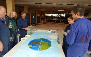 MitarbeiterInnen von Daimler Logistics malen gemeinsam während einer kreativen Teambuilding Aktion ihre neuen Kulturelemente