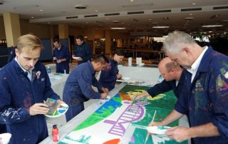 MitarbeiterInnen von Daimler Logistics malen gemeinsam während einer kreativen Teambuilding Aktion ihre neuen Kulturelemente